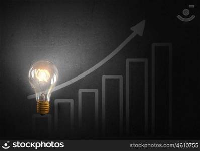 Bright ideas on wall. Glowing glass light bulb hanging from above and business sketches at dark background