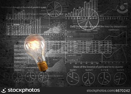 Bright ideas on wall. Glowing glass light bulb hanging from above and business sketches at dark background