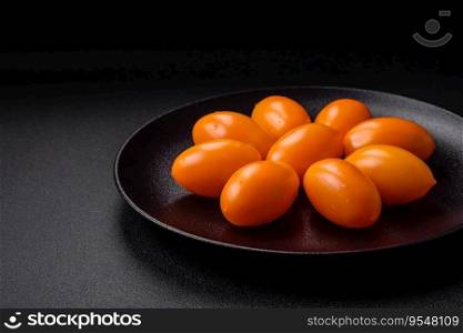 Bright juicy fresh yellow plum-shaped tomatoes on a black textured concrete background