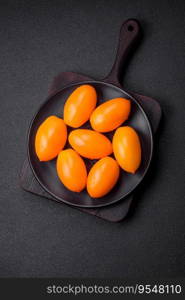 Bright juicy fresh yellow plum-shaped tomatoes on a black textured concrete background