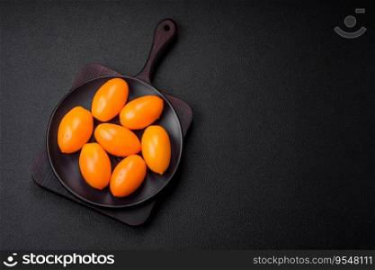 Bright juicy fresh yellow plum-shaped tomatoes on a black textured concrete background