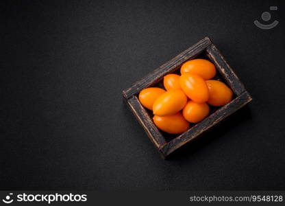 Bright juicy fresh yellow plum-shaped tomatoes on a black textured concrete background