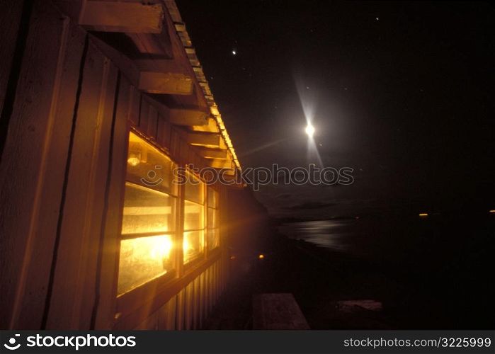 Bright Light In The Night Sky Over A Lakeside Cabin