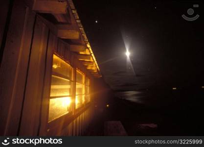 Bright Light In The Night Sky Over A Lakeside Cabin
