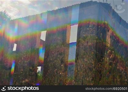 Bright light leaking through the windows of an abandoned house and overgrown plants. Abstract prism distortion on sunny day.
