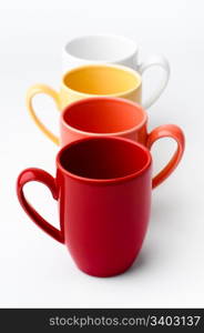 Bright mugs. Perspective row of bright colorful mugs, red, orange, yellow and white, on a white background