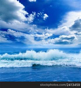 Bright ocean landscape in blue tones. Sea waves and beautiful sky with white clouds.