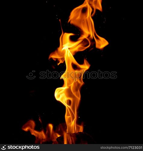 bright orange and yellow flames with sparks on black background, close up