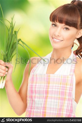 bright picture of beautiful housewife with spring onions over green.