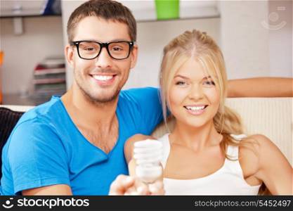 bright picture of happy couple holding energy saving bulb (focus on man)