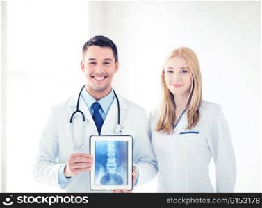 bright picture of two doctors showing x-ray on tablet pc. two doctors showing x-ray on tablet pc