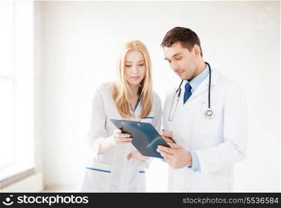 bright picture of two young attractive doctors pointing at blank paper