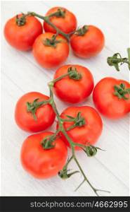 Bright picture of vine tomatoes on a white wooden background