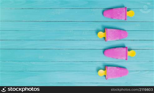 bright pink frozen popsicles yellow sticks wooden background