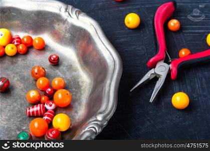 Bright plastic beads. Orange plastic beads for needlework in a stylish tray