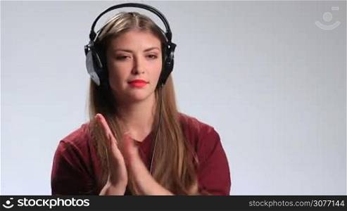Bright positive hipster girl with headphones enjoying her favorite track on mp3 player. Playful young brunette woman going crazy of her favorite song, clapping her hands in rhythm of melody, gesturing, making positive facial expressions and smiling