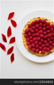bright raspberry pie and red flower petals. bright raspberry cake on a plate