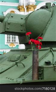 Bright red carnations on a green background of the Soviet T-34.