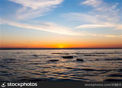 Bright sky , birds, rocks and water at sunset over sea