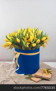 Bright spring bouquet of tulips and yellow mimosa flowers in blue box. Bright spring bouquet of tulips and mimosa flowers