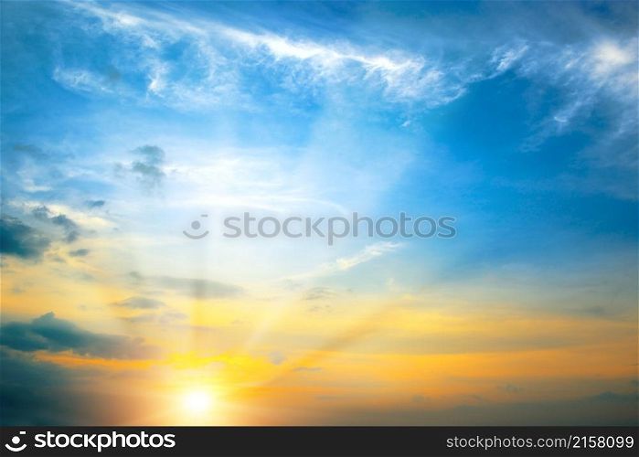 Bright spring sunset with blue sky, red sun and sunbeams.
