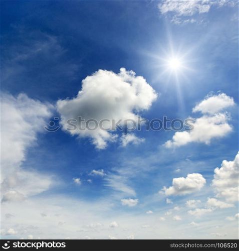 Bright sun and clouds on the background of an epic dark blue sky.