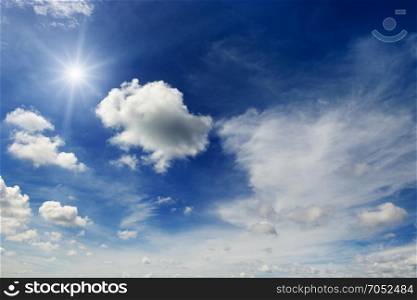 Bright sun and white clouds on the background of an epic dark blue sky.