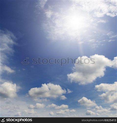 Bright sun in the blue sky amongst white clouds.