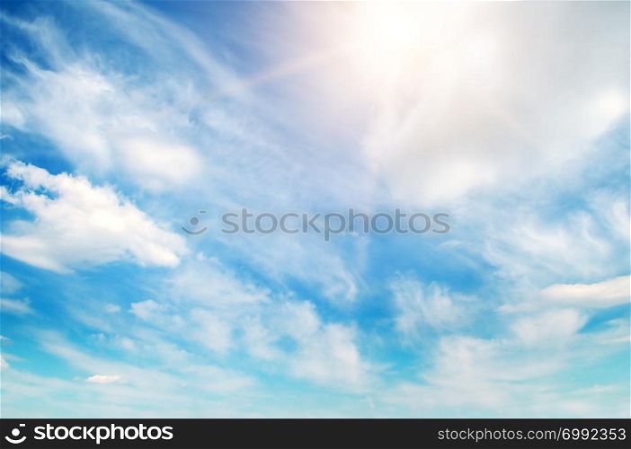 Bright sun on blue sky with white clouds.
