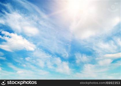 Bright sun on blue sky with white clouds.