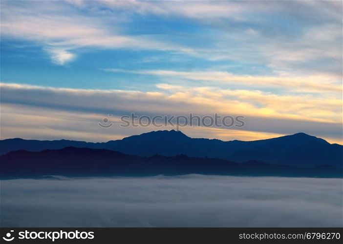 Bright sunrise, the mist in a mountain valley and mountain peaks on the horizon.