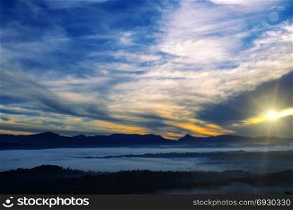 Bright sunrise, the mist in a mountain valley and mountain peaks on the horizon.