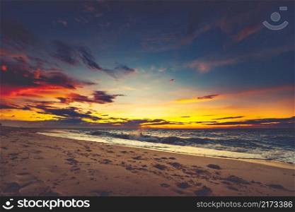 Bright sunset over the Asian shoreline. Stunning landscape. Breathtaking cloudy colorful sky over the ocean and the beach. The footprints on the sand surface. Ideal image for the backgrounds.. Bright sunset over the Asian shoreline.