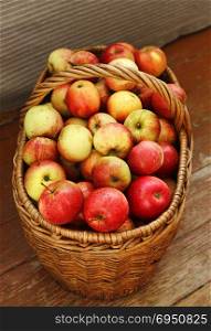 Bright tasty ripe apples in a basket on the wooden floor