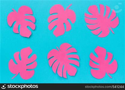 Bright trendy pink tropical leaves monstera of paper on blue background. Flat lay Top-view creative paper art.. Bright trendy pink tropical leaves monstera of paper on blue background. Flat lay Top-view creative paper art