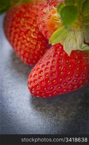 Bright, vibrant red strawberries close up on dark bench top