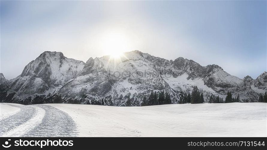 Bright winter landscape with snow-capped Alps mountain peaks, snow-covered nature, and snowy alpine road, on a sunny day, near Ehrwald, Austria.