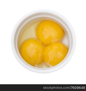 Bright yellow egg yolks in a white bowl isolated on white background