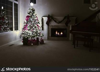 Brightly illuminated Christmas tree with glowing fireplace in home