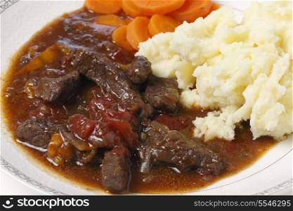 British beef and tomato casserole, served with mashed potatoes and boiled carrots, closeup