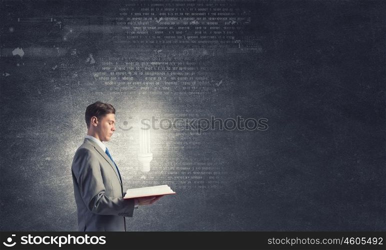 Broaden your mind. Businessman holding opened book with glass glowing light bulb