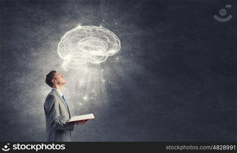 Broaden your mind. Shocked businessman holding opened book with brain picture