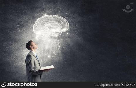 Broaden your mind. Shocked businessman holding opened book with brain picture