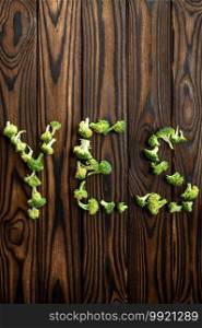 Broccoli YES word isolated on wooden background, top view. Organic vegetarian food, grocery assortment, natural eco products, healthy lifestyle concept. Broccoli YES word isolated on wooden background
