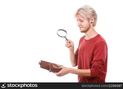 Broke young man holding magnifying glass looking for banknotes in empty wallet purse. Lack of money. Crisis and weak economy concept, isolated on white. Young man with empty wallet