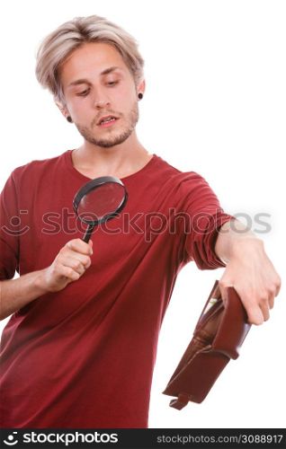 Broke young man holding magnifying glass looking for banknotes in empty wallet purse. Lack of money. Crisis and weak economy concept, isolated on white. Young man with empty wallet