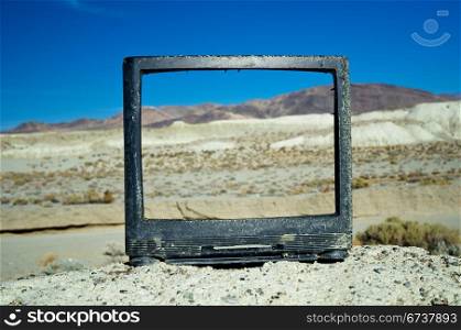 Broken and abandoned television set on a small hill in the desert.