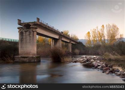 Broken bridge over a river in autumn