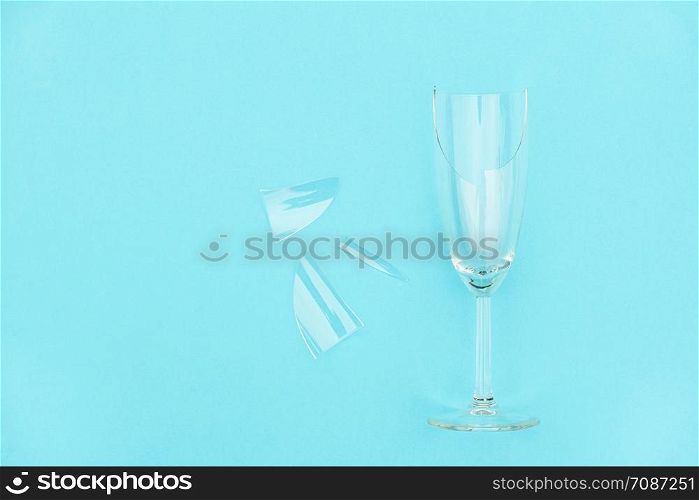 Broken champagne glass with splinters on blue background with copy space. Concept fight against alcoholism, drunkenness and refusal of alcohol. Creative Top view Flat lay.. Broken champagne glass with splinters on blue background with copy space. Concept fight against alcoholism, drunkenness and refusal of alcohol. Creative Top view Flat lay