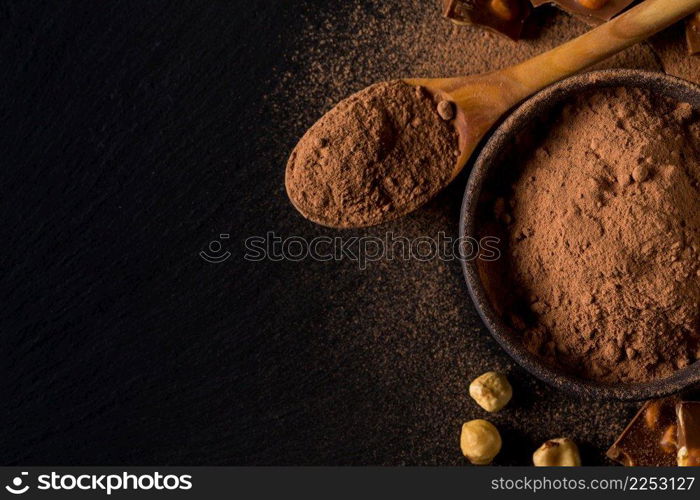 Broken chocolate nuts pieces and cocoa powder on dark background